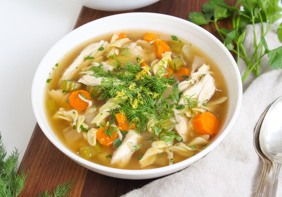 crockpot chicken noodle soup in a bowl with herbs