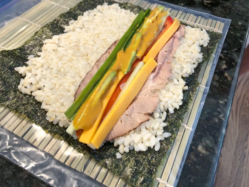 sushi with roast beef, avocado, cucumber, cheddar cheese, red pepper, and mustard soy sauce