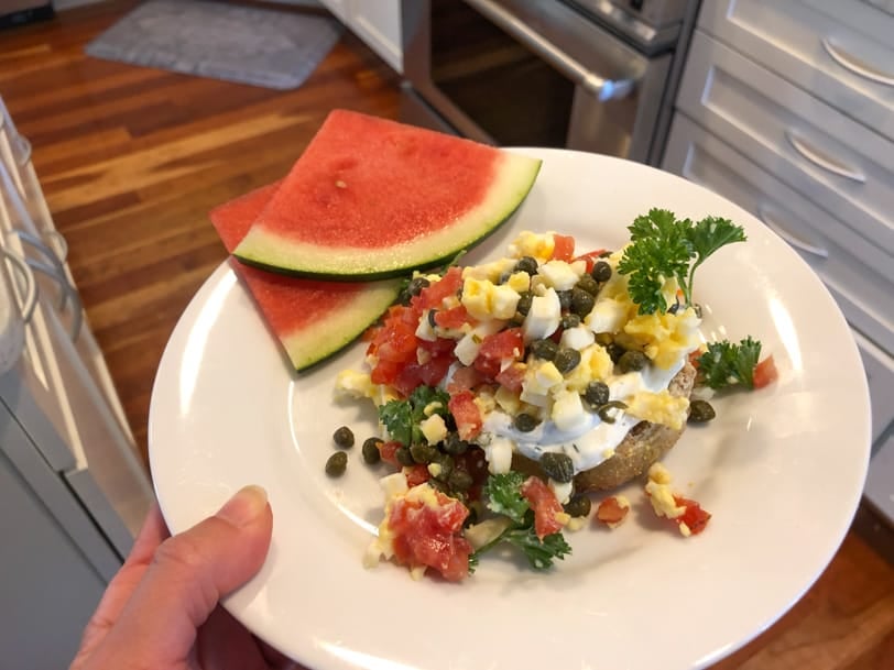 English muffin with capers, hard boiled egg, and tomato with watermelon