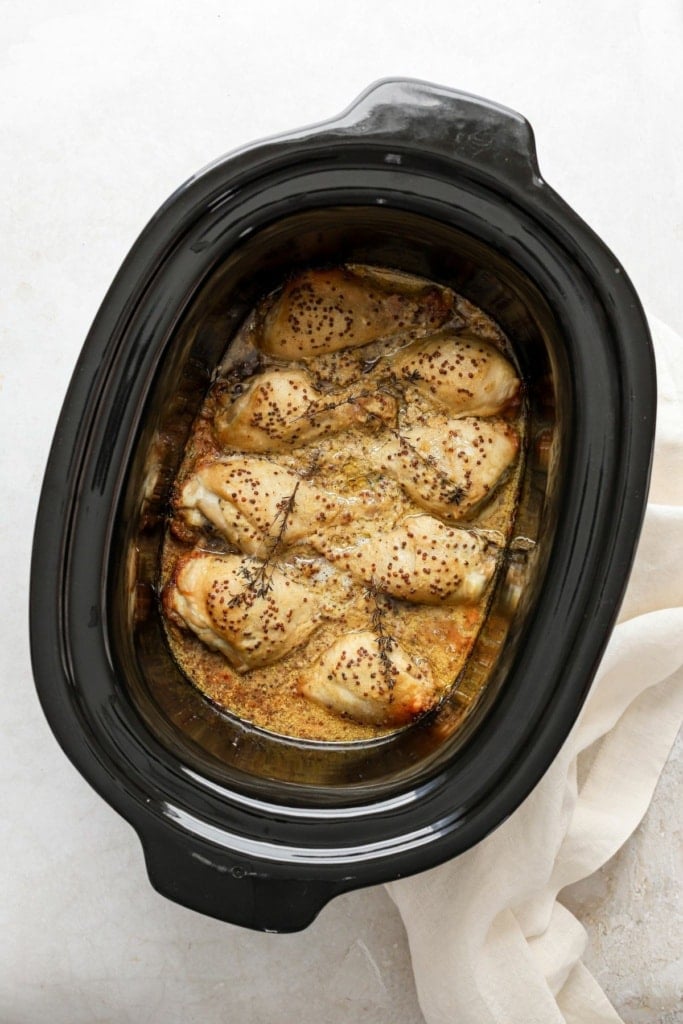 cooked honey mustard chicken in a slow cooker insert